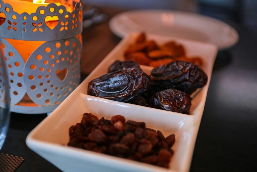 صورة تمر وزبيب ومكسرات بجانب فانوس مضاء في أجواء رمضان